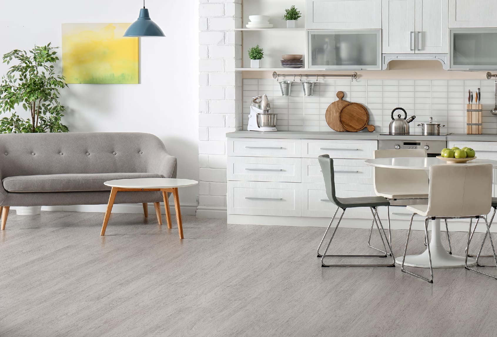 Lantai Vinyl TV 2005 Silver Oak di Dapur dan Ruang Tamu Modern - Penerapan lantai vinyl dengan desain Silver Oak yang cerah di dapur dan ruang tamu modern, dilengkapi dengan perabotan dapur putih, sofa abu-abu, dan meja makan minimalis, menciptakan suasana interior yang bersih, terang, dan elegan.